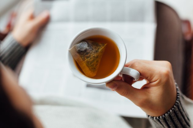 Man holding cup of tea and reading the newspapers