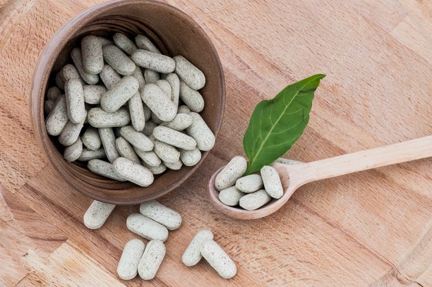 Alternative pills on a wooden spoon and in a bowl