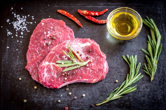 Fresh beef steaks with ingredients on the dark background