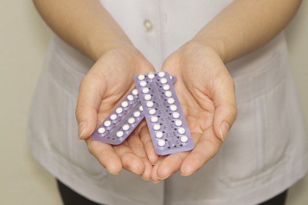 doctor's hand holding the birth control pills