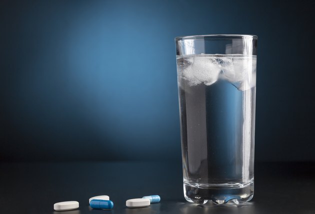 Medicine pills and glass of cold drink water