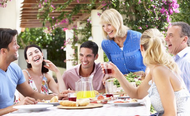 Group Of Young And Senior Couples Enjoying Family Meal