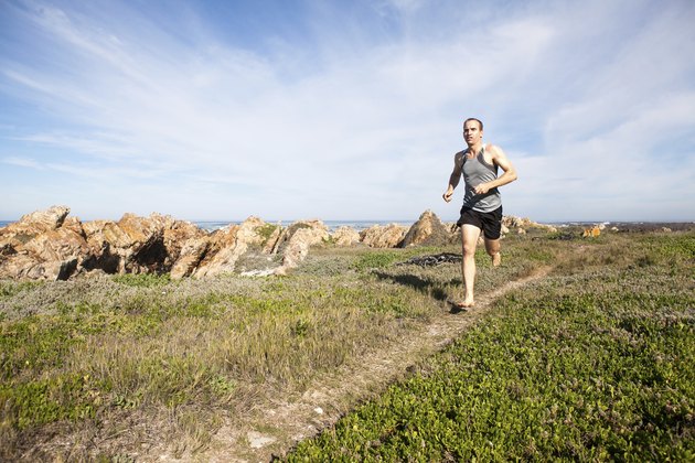 Male athlete running barefoot and fast on a walking trail