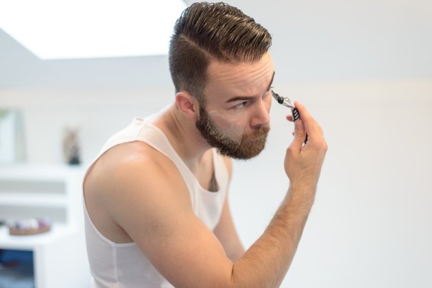 Young man shaving above his beard