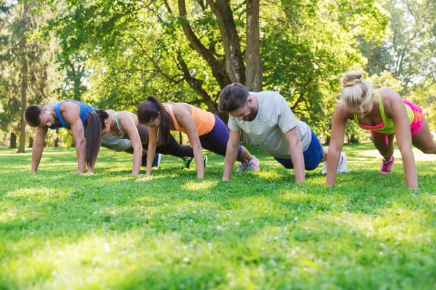 fitness, sport, friendship and healthy lifestyle concept - group of teenage friends or sportsmen exercising and doing push-ups at boot camp