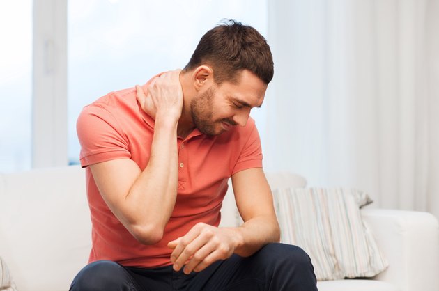 unhappy man suffering from neck pain at home