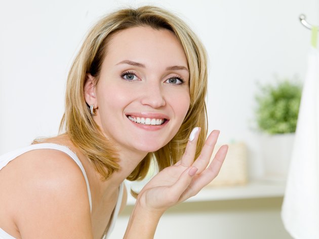 girl applying moisturizer cream on face