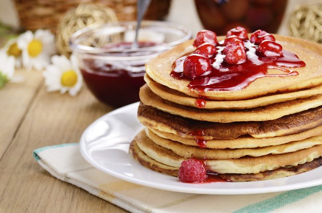 Delicious pancakes with raspberries on the wooden kitchen table