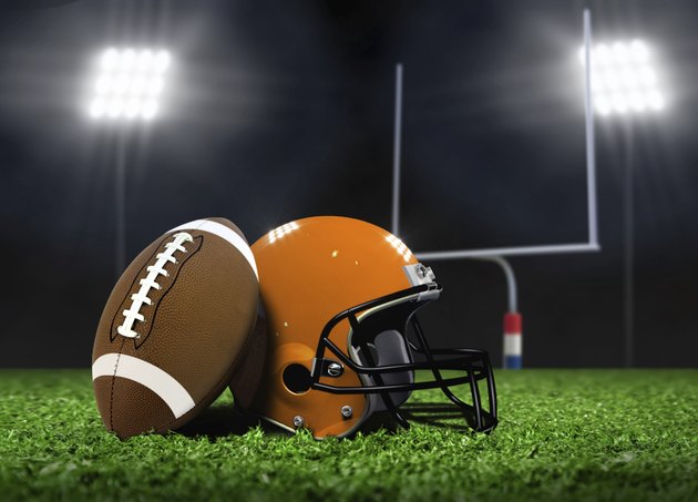 Football Ball and Helmet On Grass under Spotlights