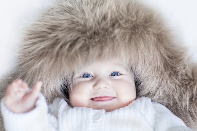 Funny baby girl with blue eyes wearing huge winter hat