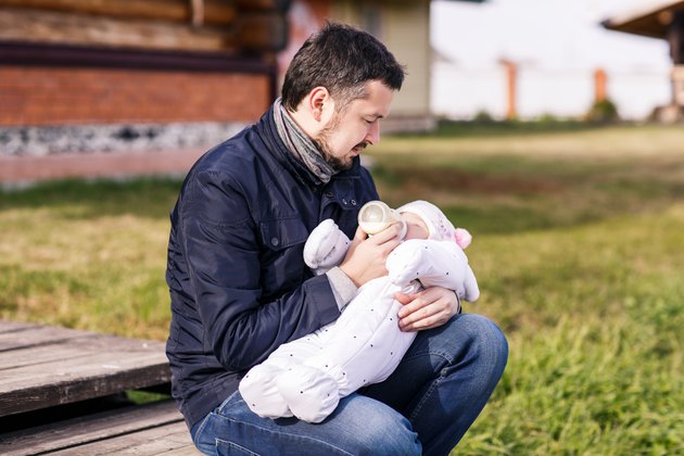 Portrait of father feeding newborn baby