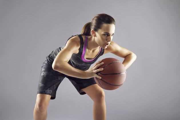 Young woman basketball player on grey background