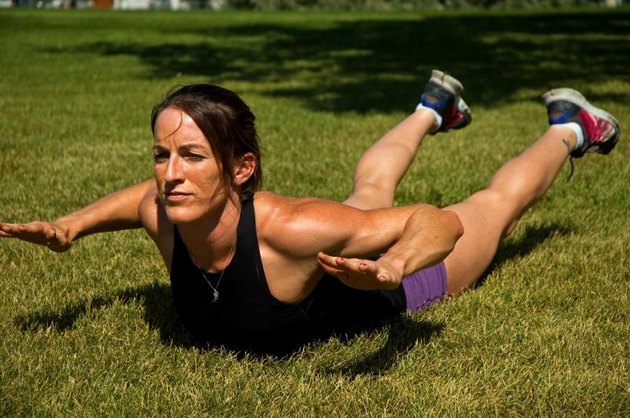 Woman doing a Superman back extension at a park.