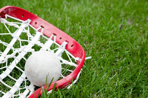 Girls lacrosse head and grey ball on grass
