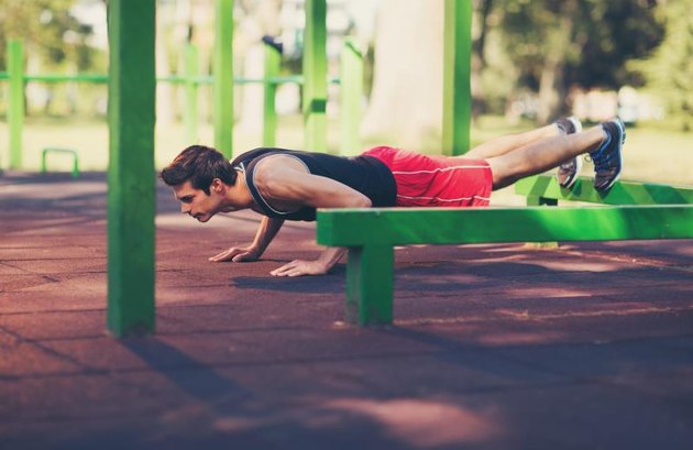 Picture of a young athletic man doing push ups outdoors.