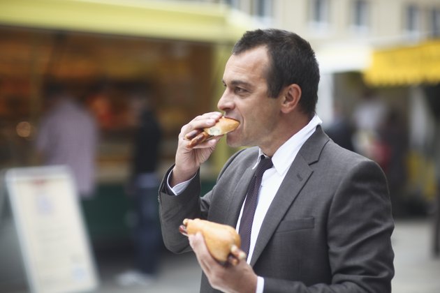 Businessman eating hotdog outside