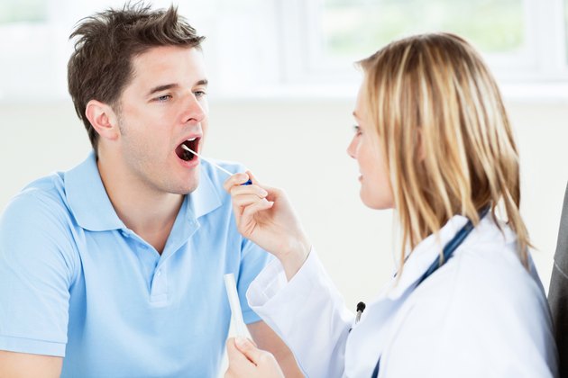 Caucasian female doctor taking a saliva sample of a male patient using cotton-bud