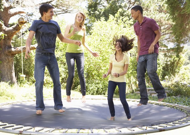 Four Teenage Friends Jumping On Trampoline In Garden