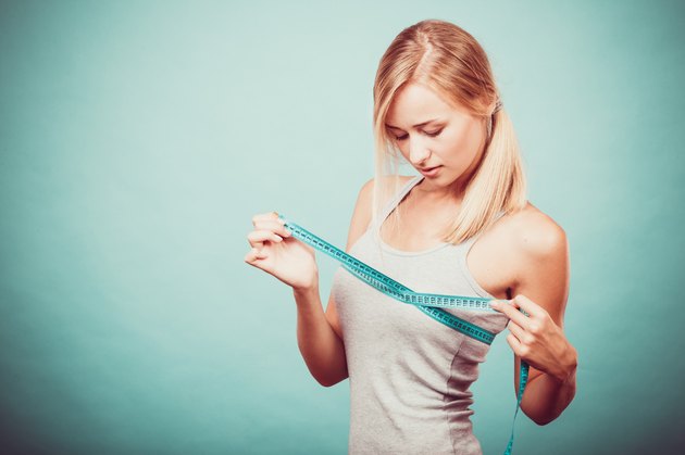 Fitness girl measuring her breasts