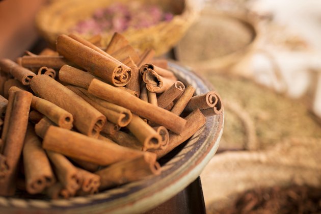 Cinnamon sticks on plate and other spices in background in spice market