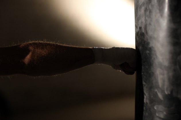 Hand of boxer and punching bag over black background