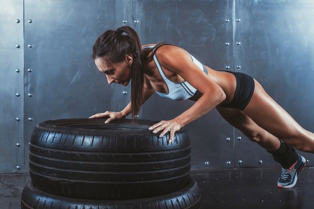 Sportswoman. Fit sporty woman doing push ups on tire strength