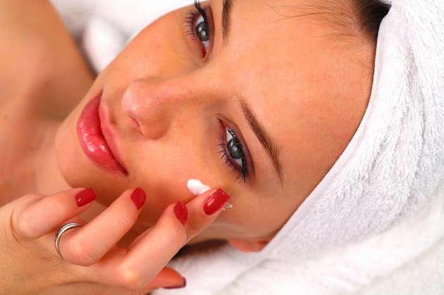 Woman applying moisturizing cream on her face