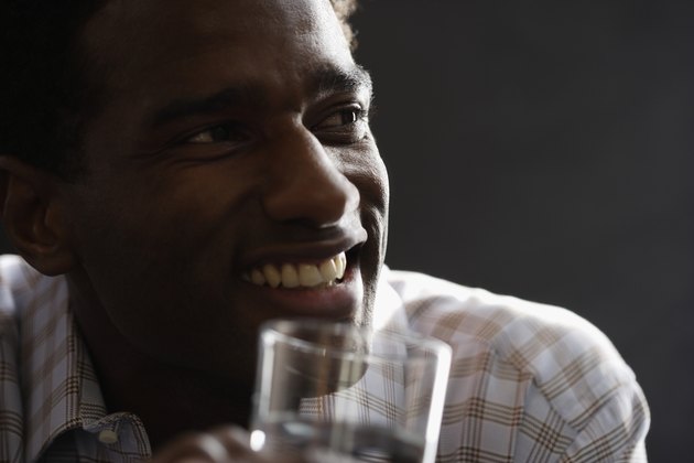 Close-up of a mid adult man holding a glass of water smiling