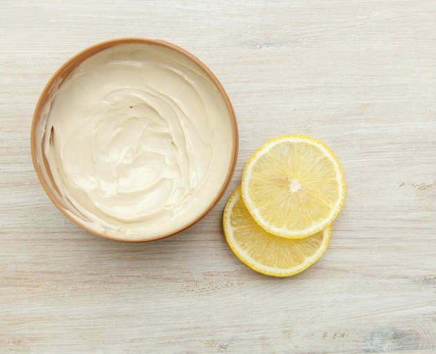 body cream and lemon slices on the wooden table