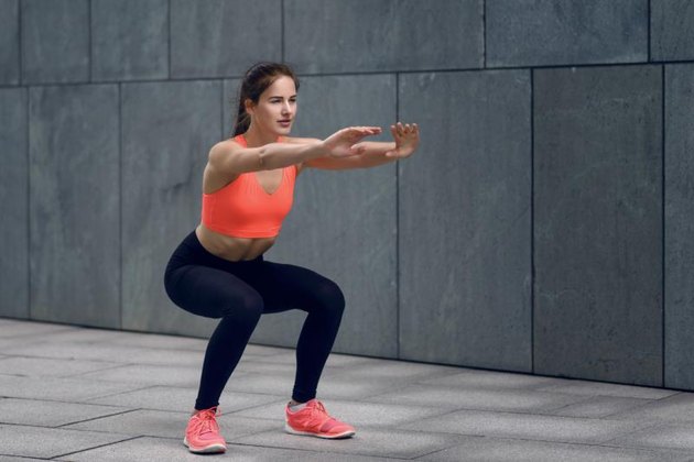 Fit young woman doing squats, strengthening her core, working out on a mat, lifestyle and health concept