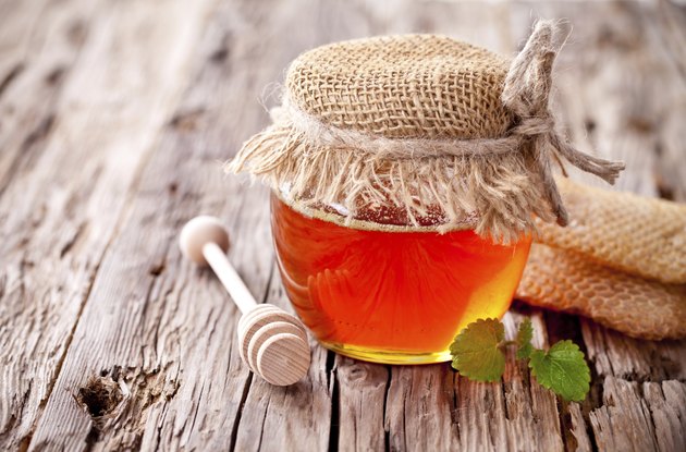 Honey in jar with honeycomb and wooden drizzler