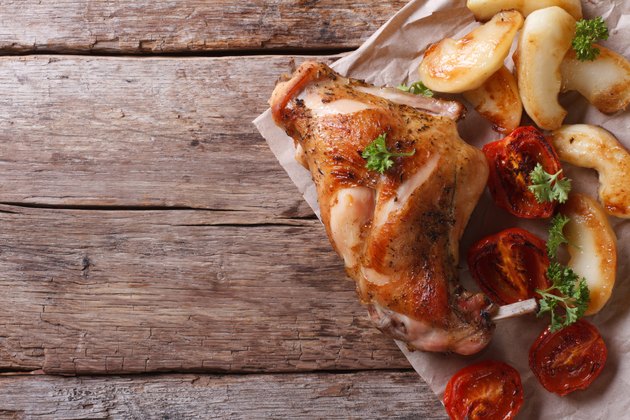 roast leg of rabbit with apples and tomatoes top view