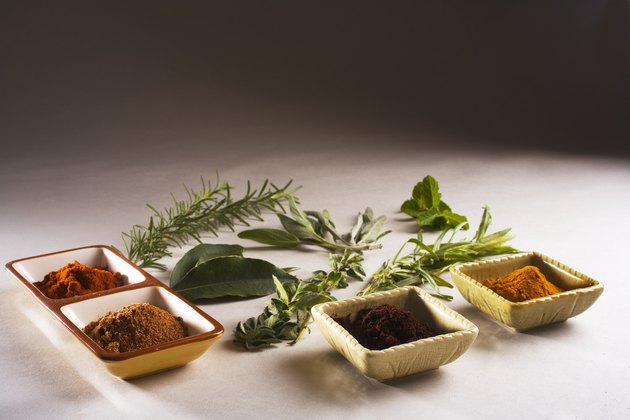 Barbecue scene, fresh herbs and spices laid out on white background.