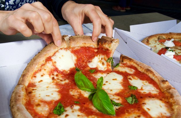 Fingers breaking apart pizza