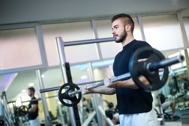 Muscular Bodybuilder Men Doing Exercises with Dumbbells in Gym