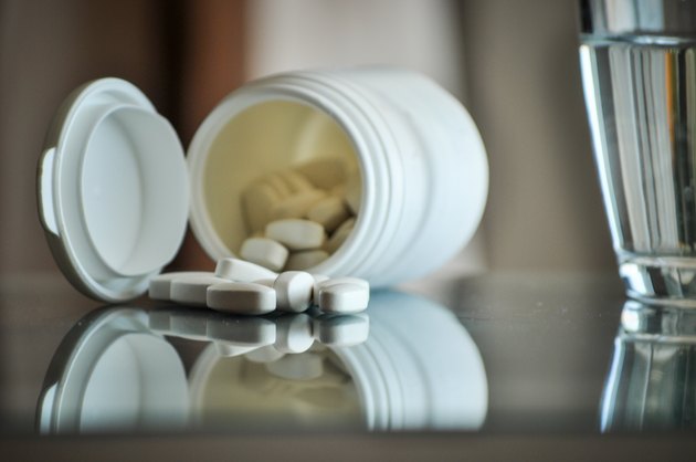 pills with pill bottle and glass of water