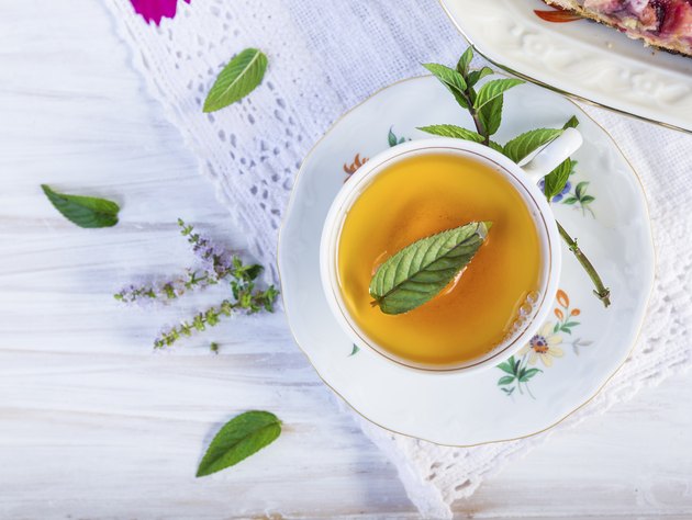 Cup of tea with peppermint on lacy napkin.
