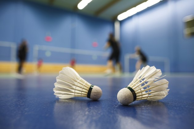 badminton courts with players competing; shuttlecocks in the foreground