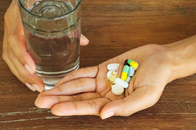 female hands holding pills, capsules, medicine,vitamin and water glass