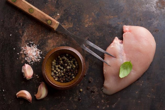 Raw chicken breast with rosemary, garlic and peppercorns, selective focus. Culinary cooking ingredients