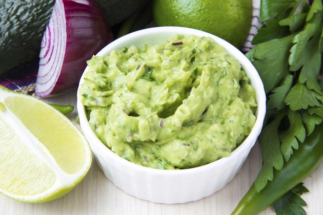 Green Mexican guacamole dip with avocado, lime, parsley, onion