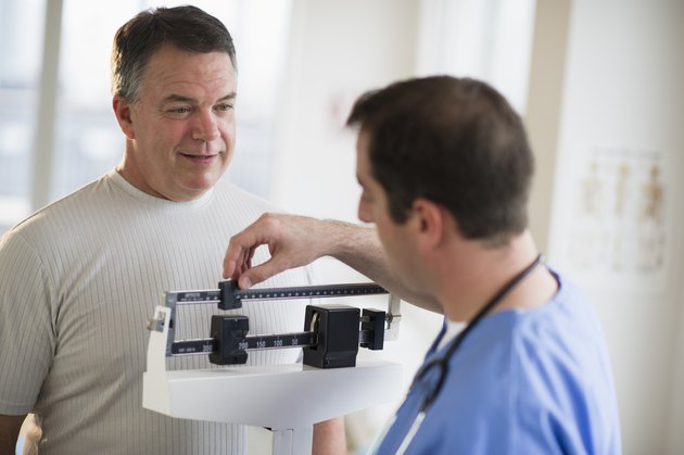 USA, New Jersey, Jersey City, Doctor assisting male patient on weighing scales in hospital
