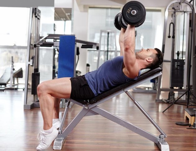 Athletic man working out his chest with dumbbells on a bench press