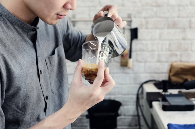 man pouring milk into his coffee