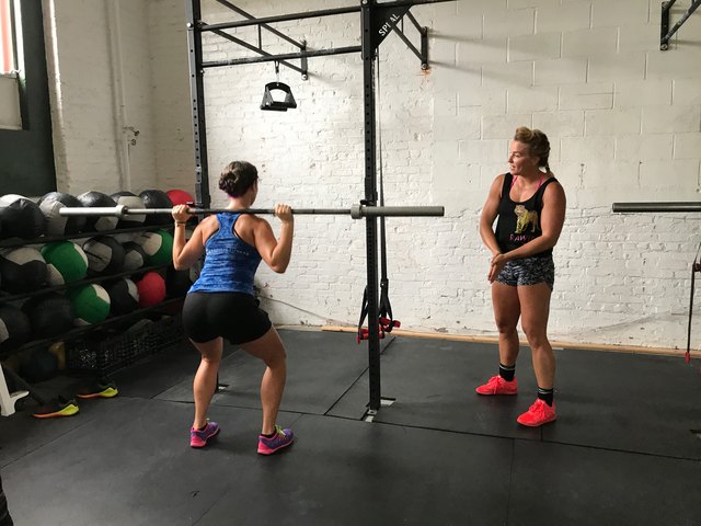 Jen Sinkler trains a woman on proper back squat technique