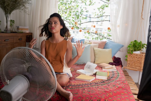 woman can’t sleep during the hot summer so she sits in front of a fan