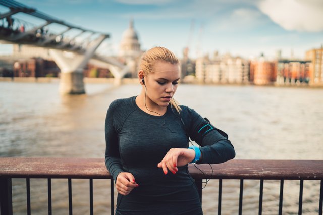 Sportswoman in UK checking pulse on smart watch during workout