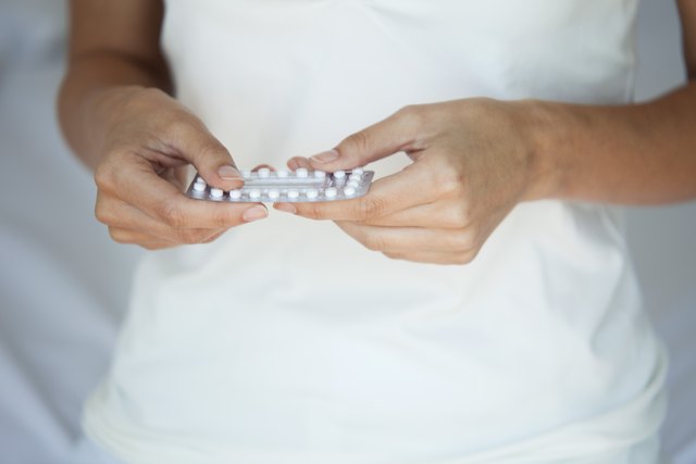 Woman holding birth control pills, mid section