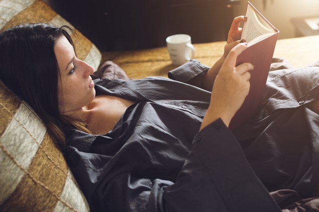 Woman relaxing in bed with her favorite book