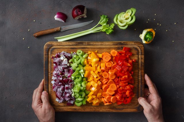 Male hands holding cutting board with sliced fresh vegetables